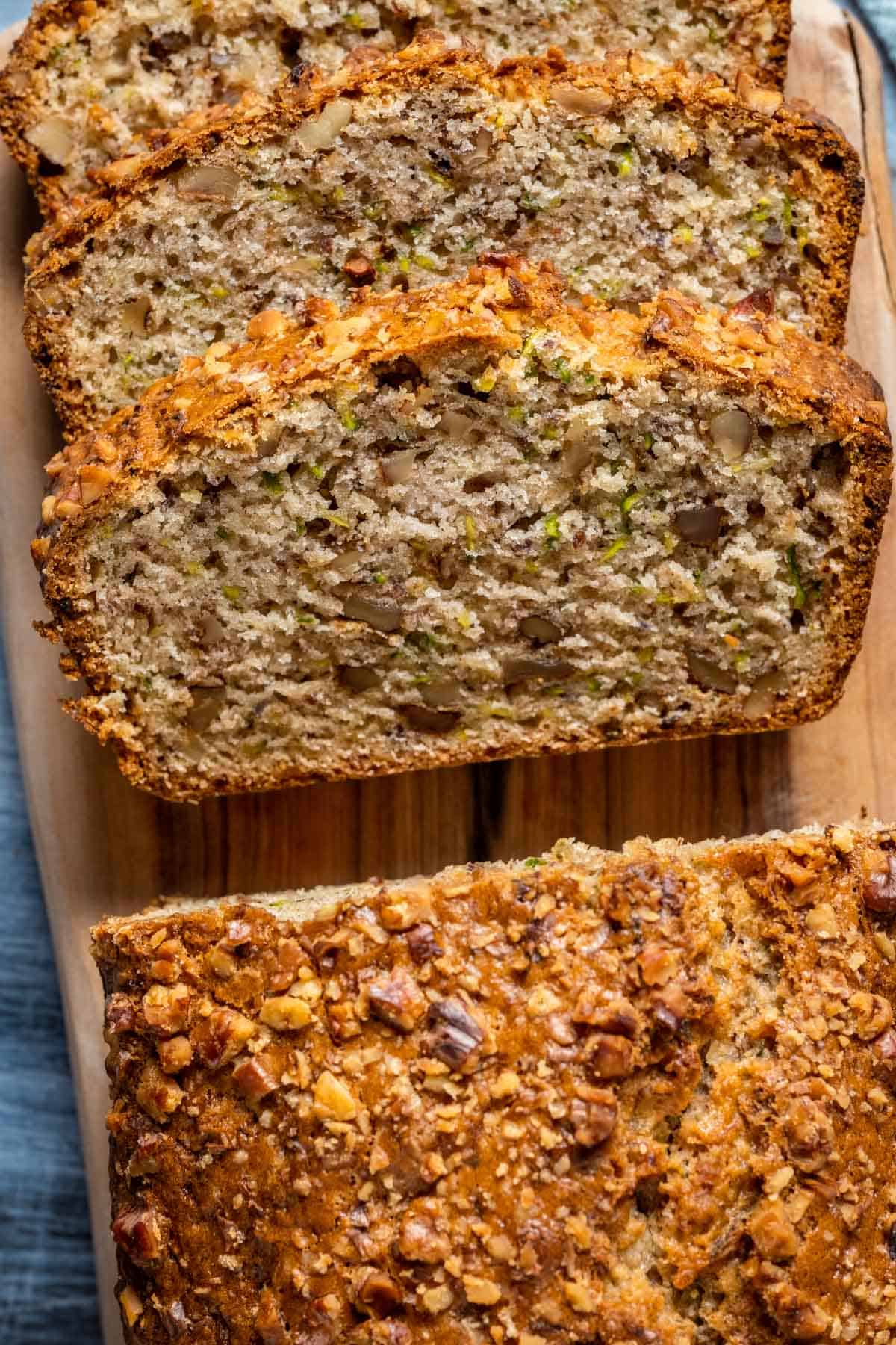 Sliced loaf of vegan zucchini bread on a wooden board.